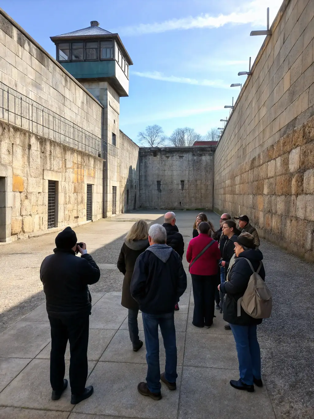 A photograph of a group of visitors being led on a guided tour of the priory, with the guide pointing out key architectural features and historical details.
